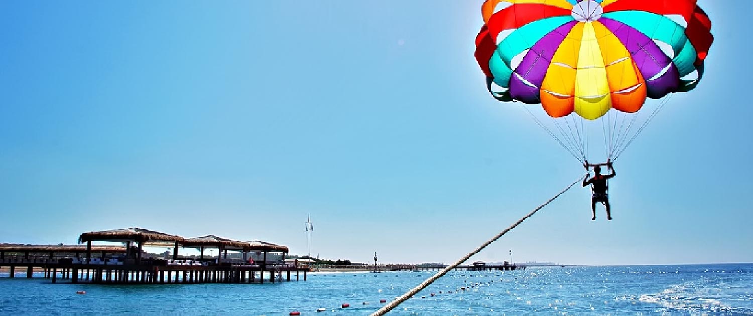 A Person Flying A Parachute Over Water