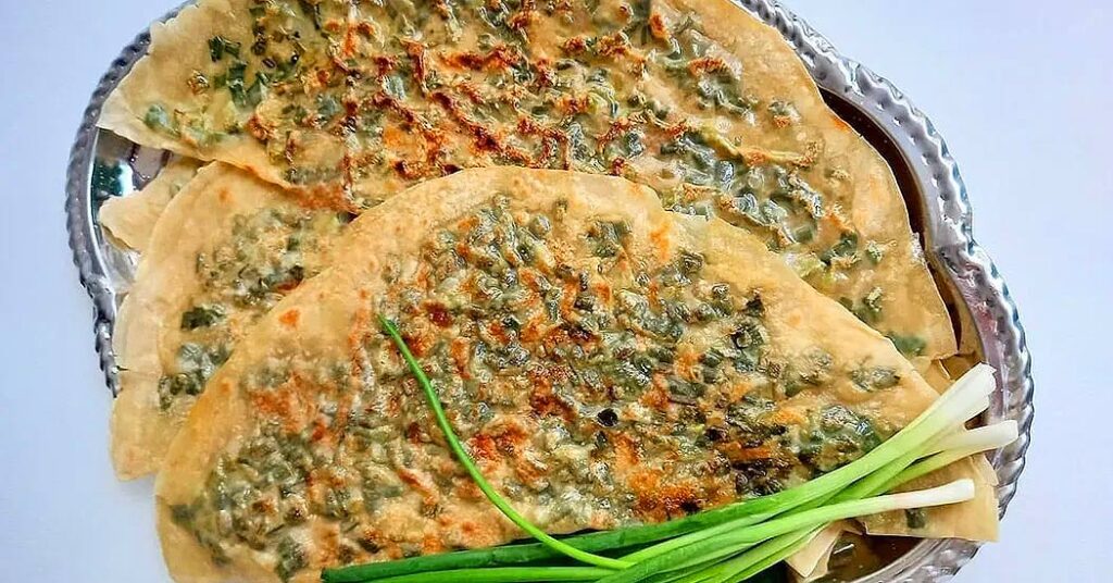 18 Popular Types Of Iranian Bread You Must Try 11 Herb-Filled Kalaneh Bread From Kurdistan, Made With Wild Herbs Like Pichak And Kinval, Offering A Nutritious And Flavorful Taste.